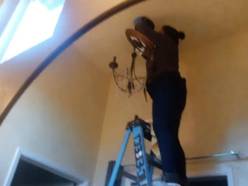 Electrician installing a chandelier in a Madison residence